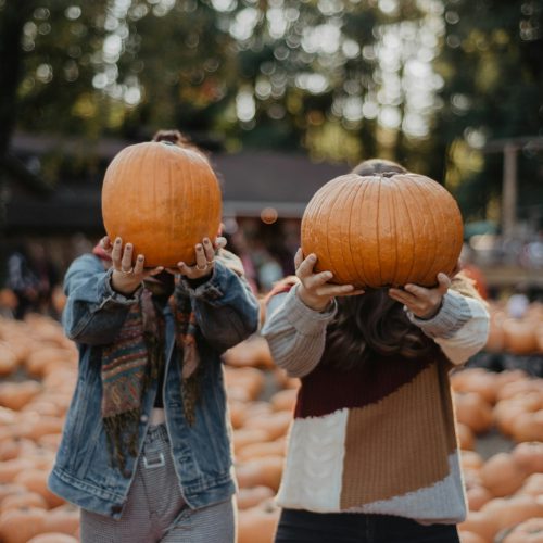 woman in blue denim jacket carrying baby in orange knit cap during daytime